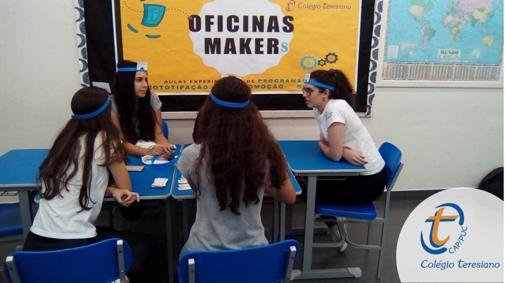 Quatro alunas do Colégio Teresiano se reúnem em uma mesa para uma atividade bilíngue de prototipação.