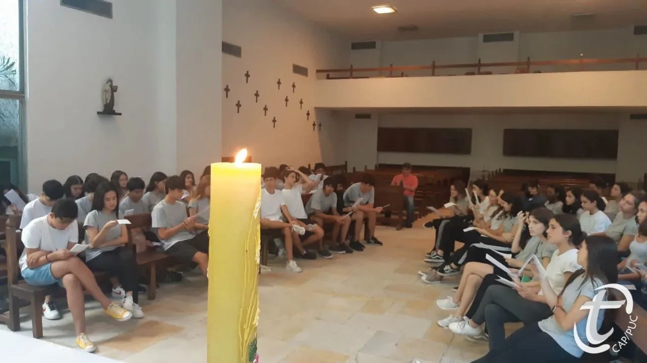 Alunos do ensino médio em aula na capela do Colégio Teresiano. Em primeiro plano, uma vela acesa.