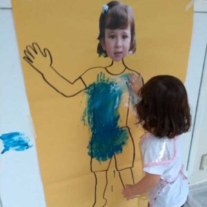 Menina de aproximadamente 4 anos fazendo uma pintura com as mãos em uma atividade lúdica sobre espiritualidade.